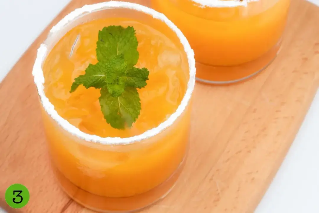 A glass of orange juice and whiskey cocktail, with a ring of powdered sugar on the rim