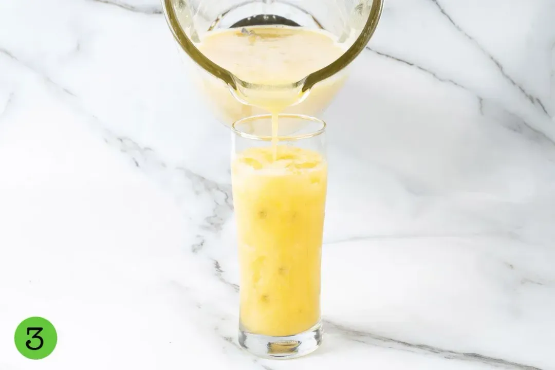 A mango passion fruit juice poured from a blender into a glass