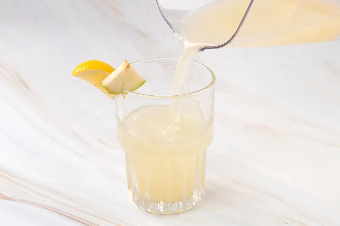 pouring pear juice from a pitcher into a glass