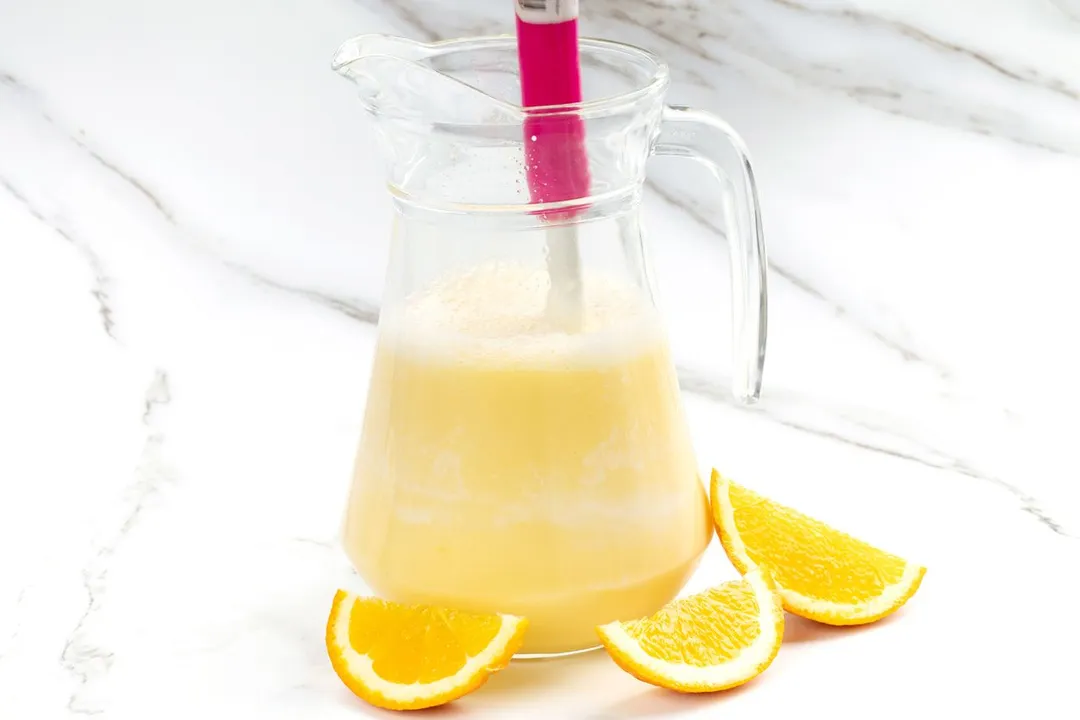 stirring orange milk mixture in a glass pitcher