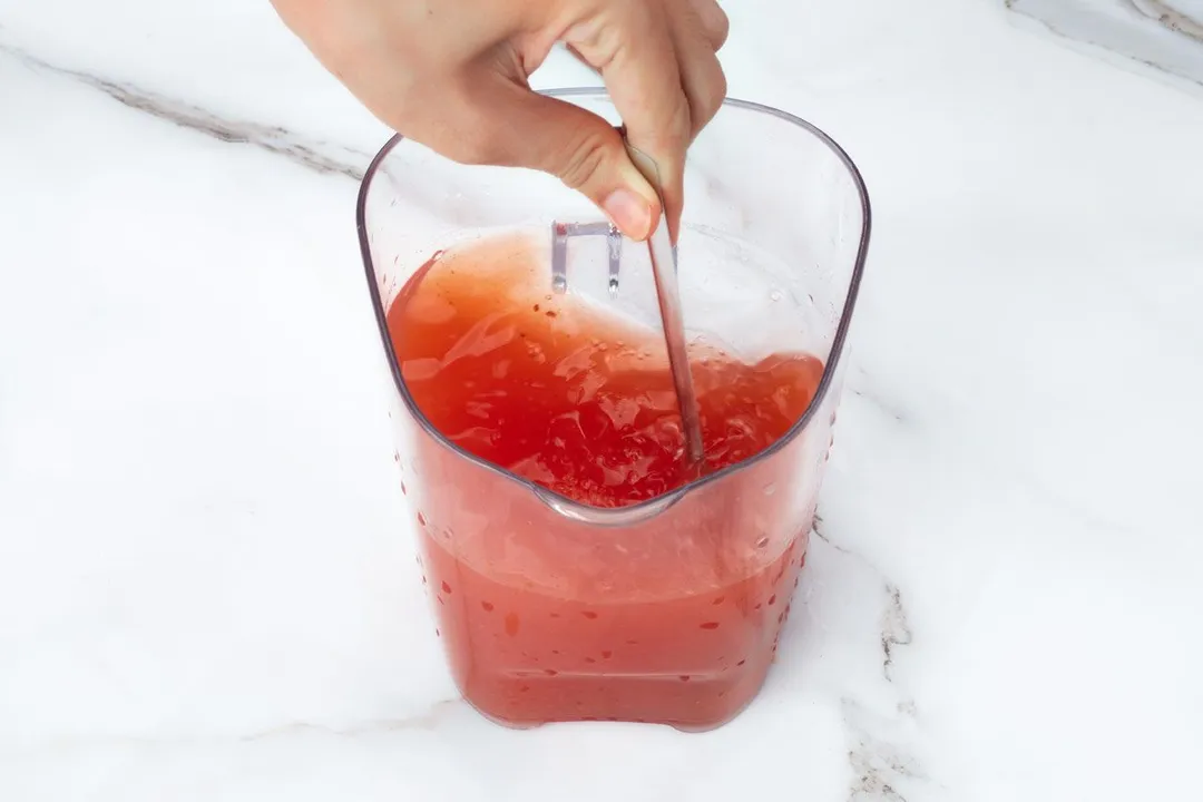 mixing red juice in a pitcher