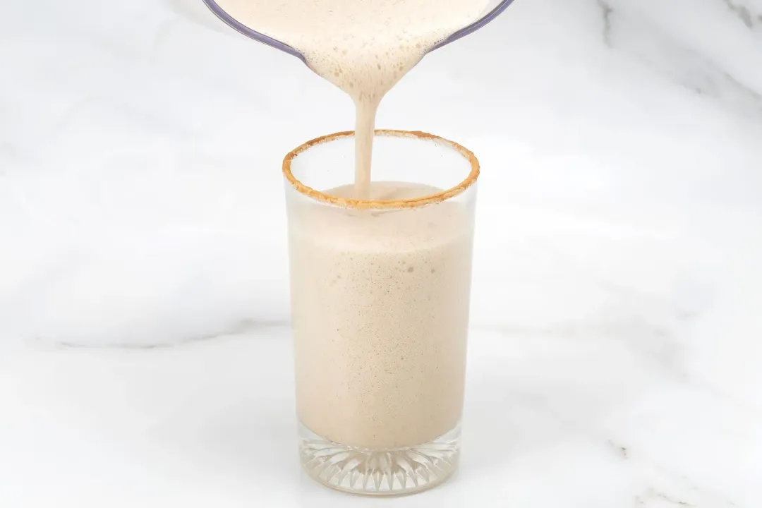 Three short classes of eggnog topped with cinnamon sticks and surrounded by star anise