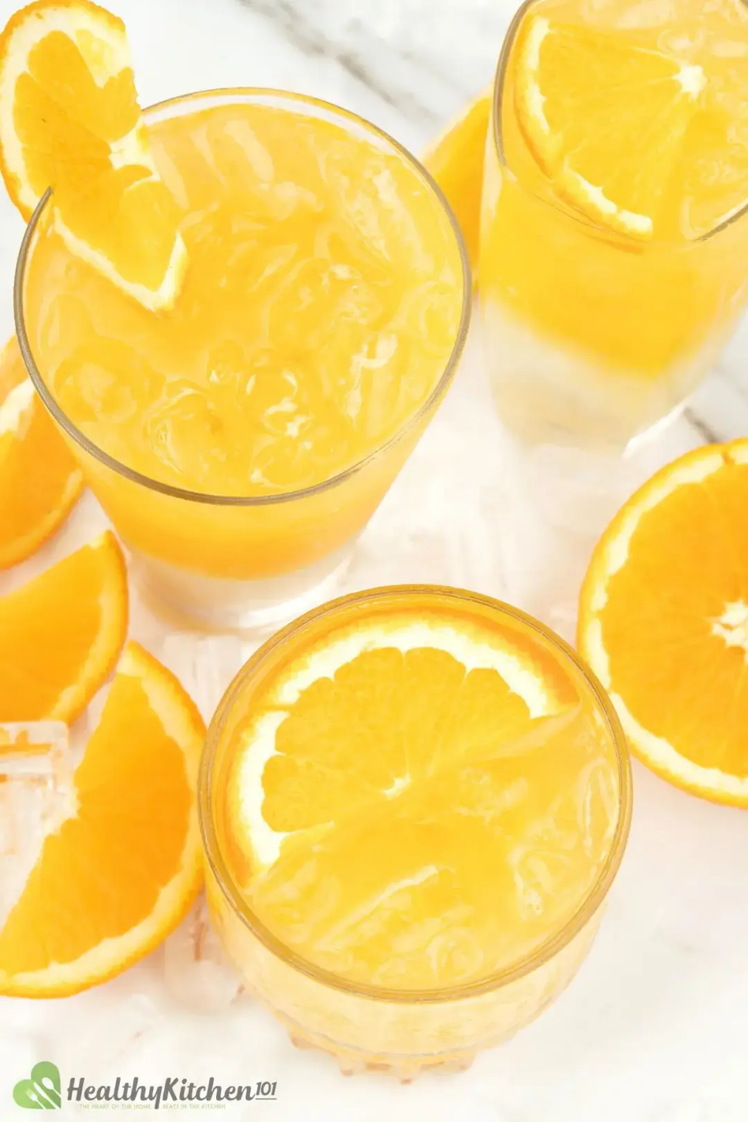 Glasses of orange juice and vodka put next to some orange wedges