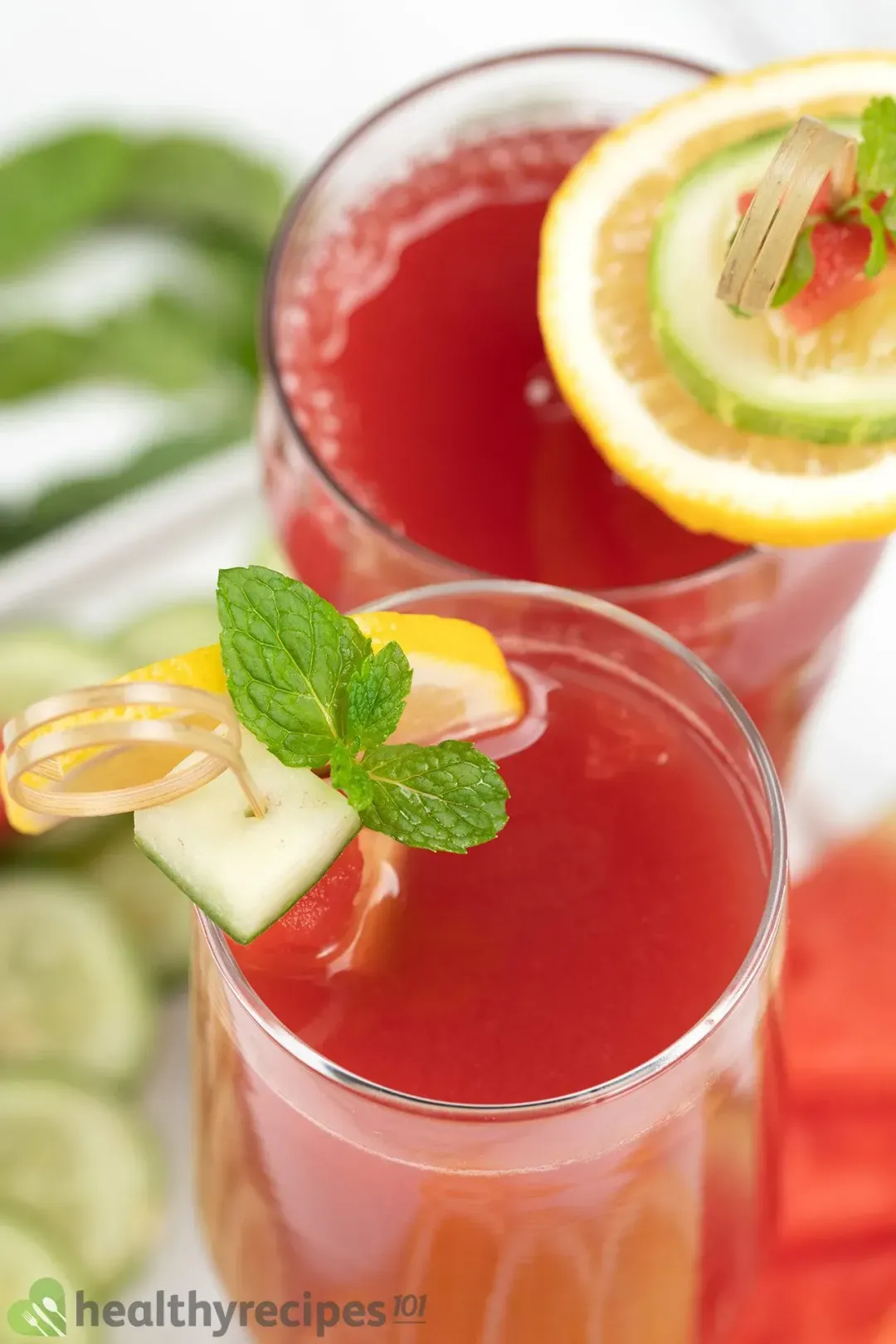 A high-angle shot of two glasses of watermelon cucumber juice decorated by garnish skewers