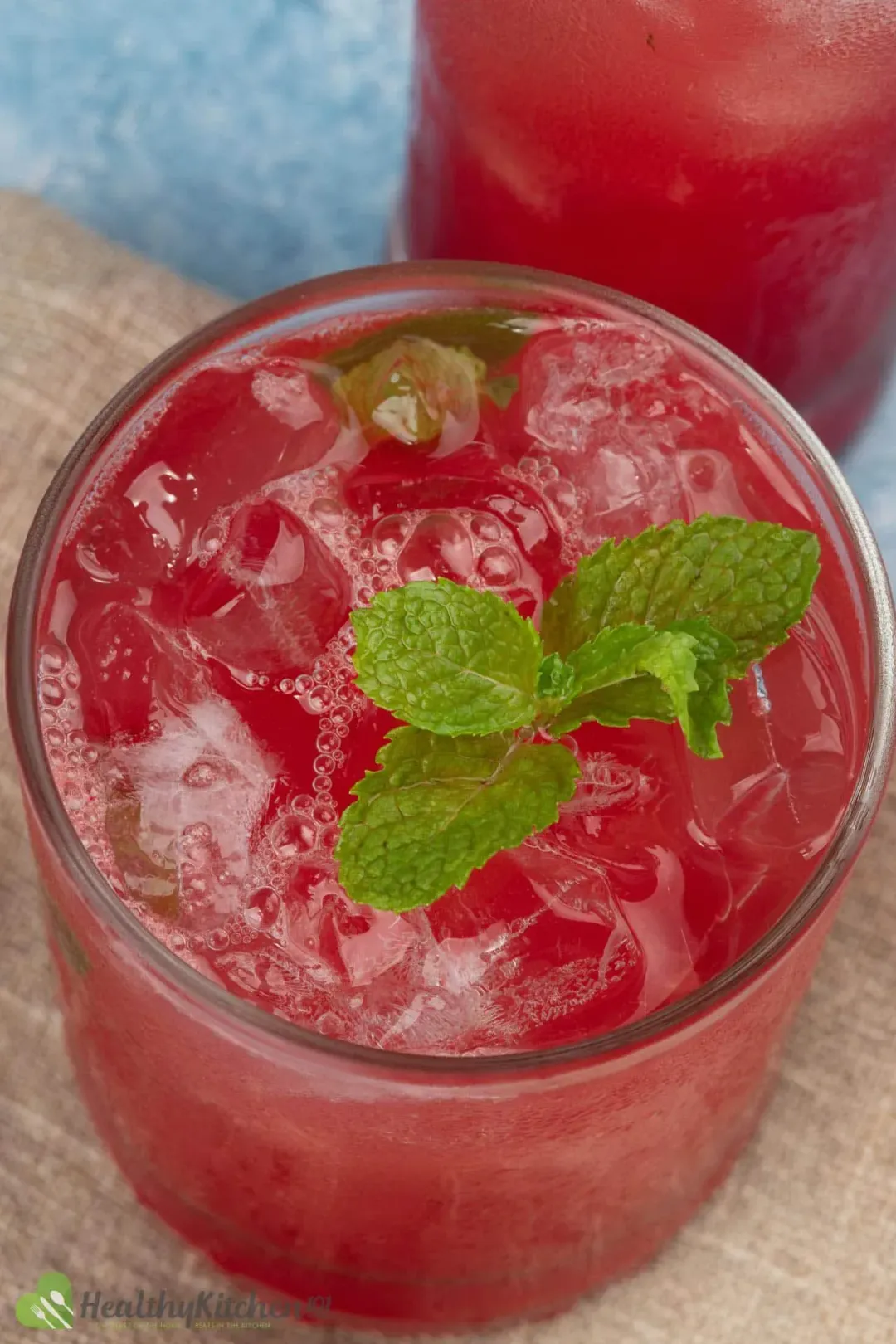 A high angle of short of a glass of watermelon juice filled with ice and have a mint leave on top