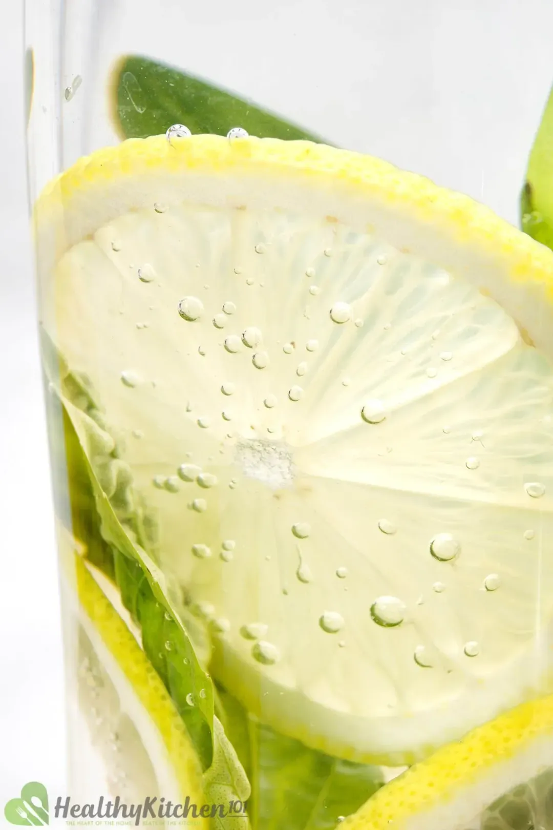 A close-up shot of a lemon wheel submerged in clear water, with air bubbles on the surface