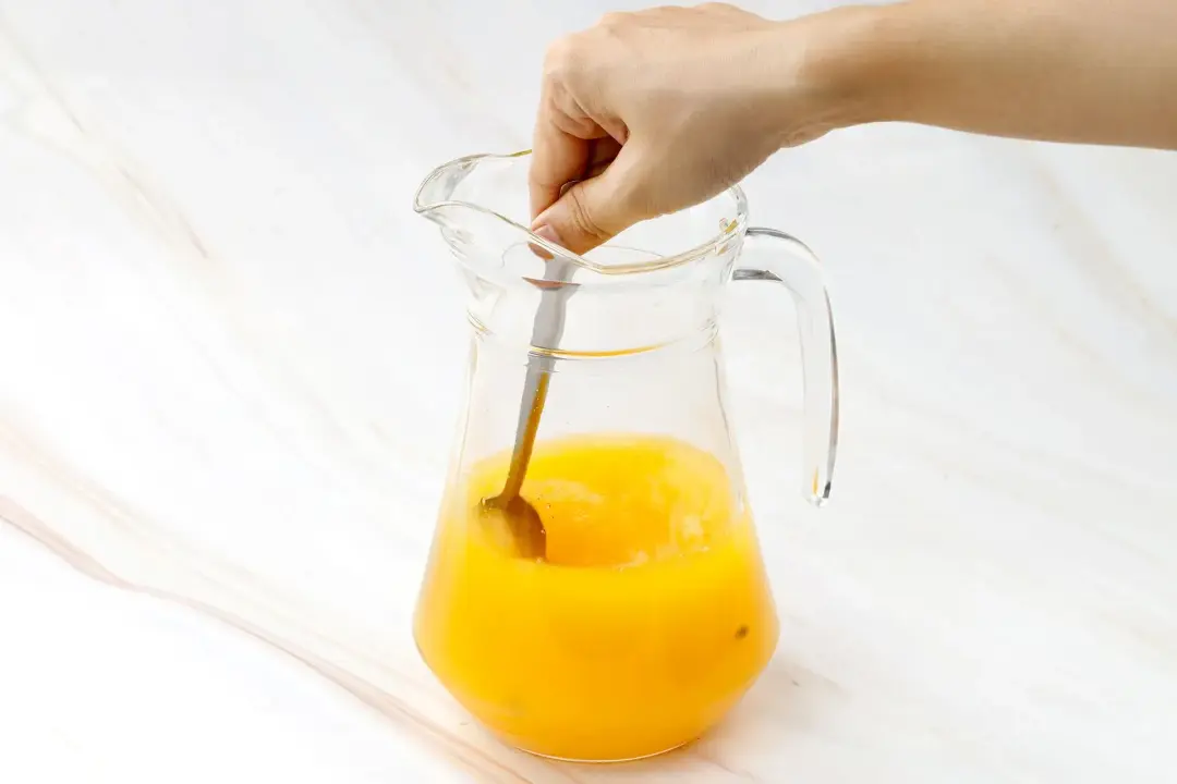 Stirring a pitcher of passion and orange juice