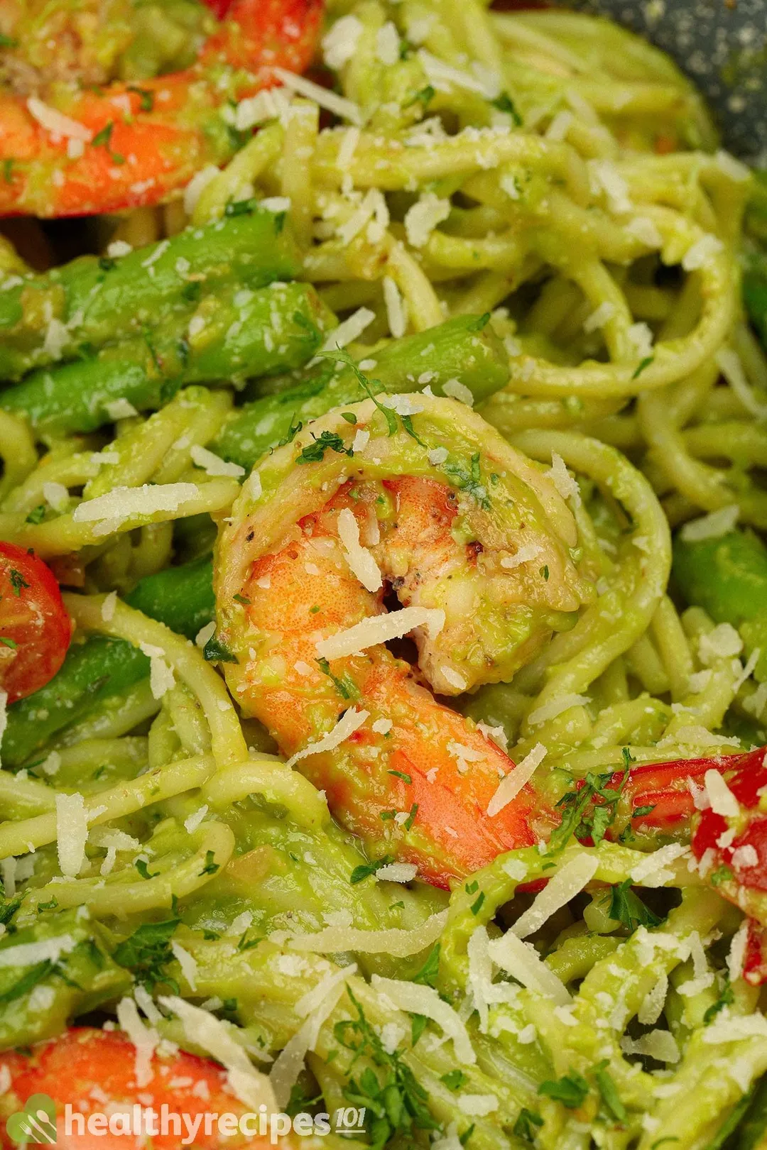 A close-up shot of avocado pasta, shrimp, and grated cheese.