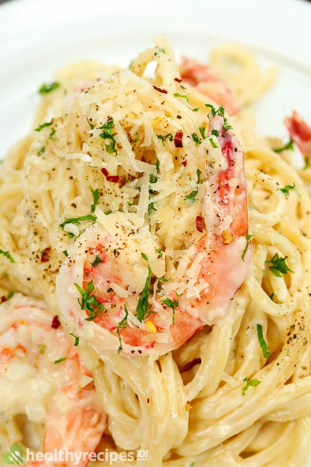 close-up shot of cooked pasta with shrimp and cheese, garnished with chopped coriander