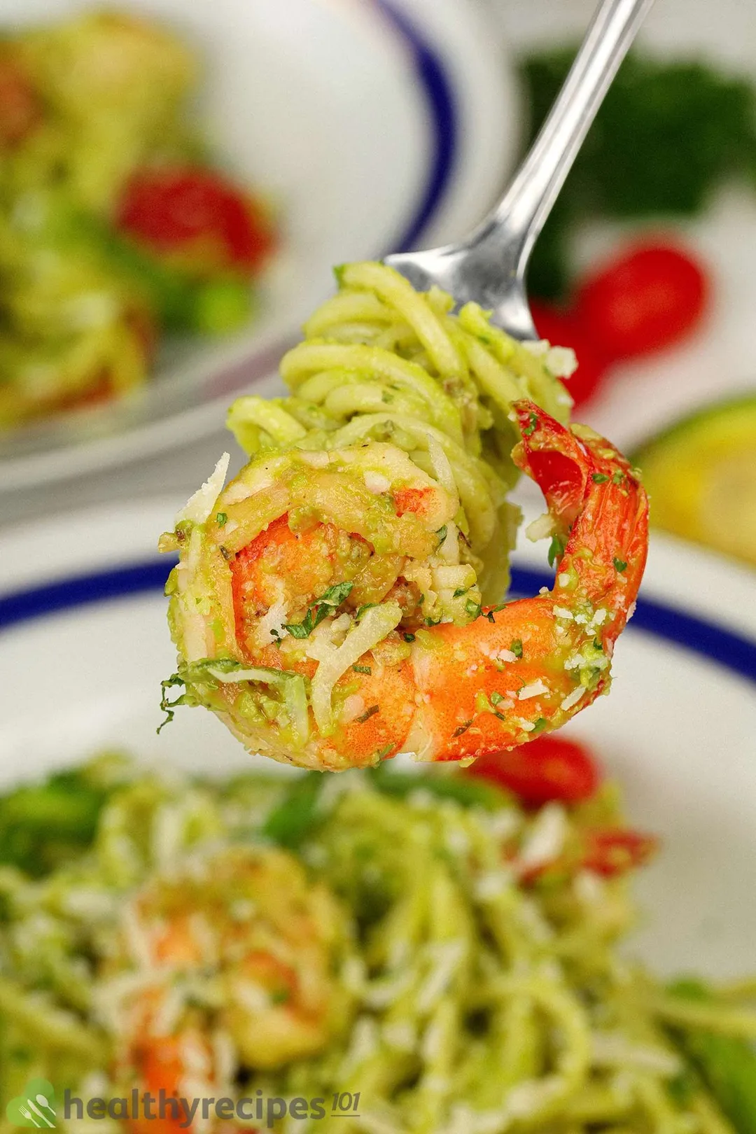 A fork wrapped with avocado pasta and piercing through a cooked shrimp.
