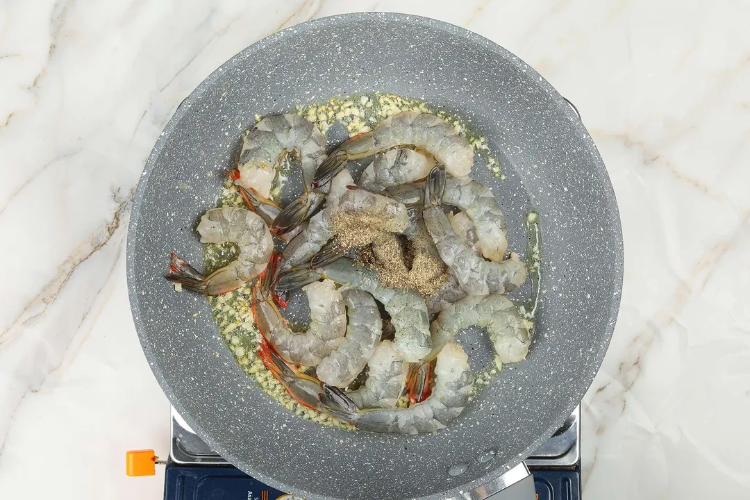 A pan cooking raw shrimp