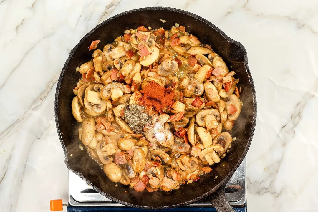 seasoning and mushroom cooking in a skillet