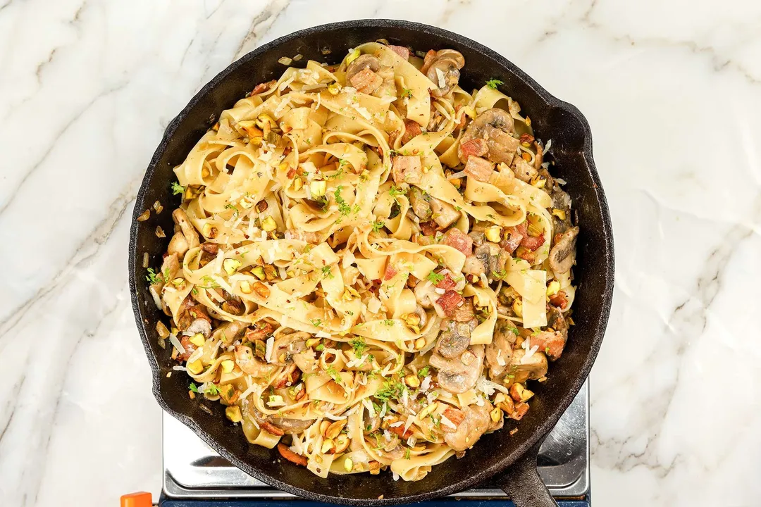 top view of a cast iron skillet of cooked mushroom pasta