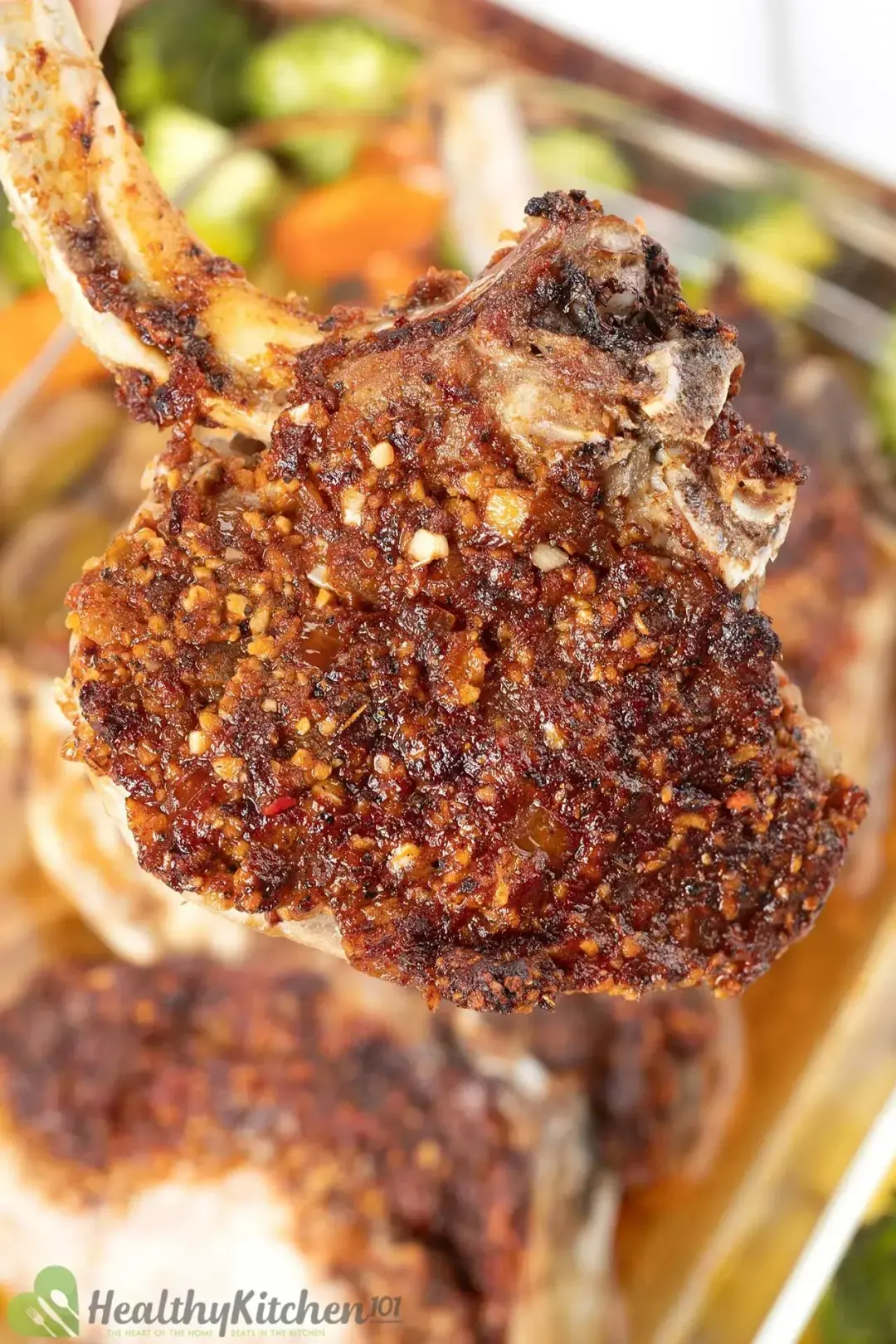 A close-up shot of a roasted pork chop with golden minced garlic and spices on the surface