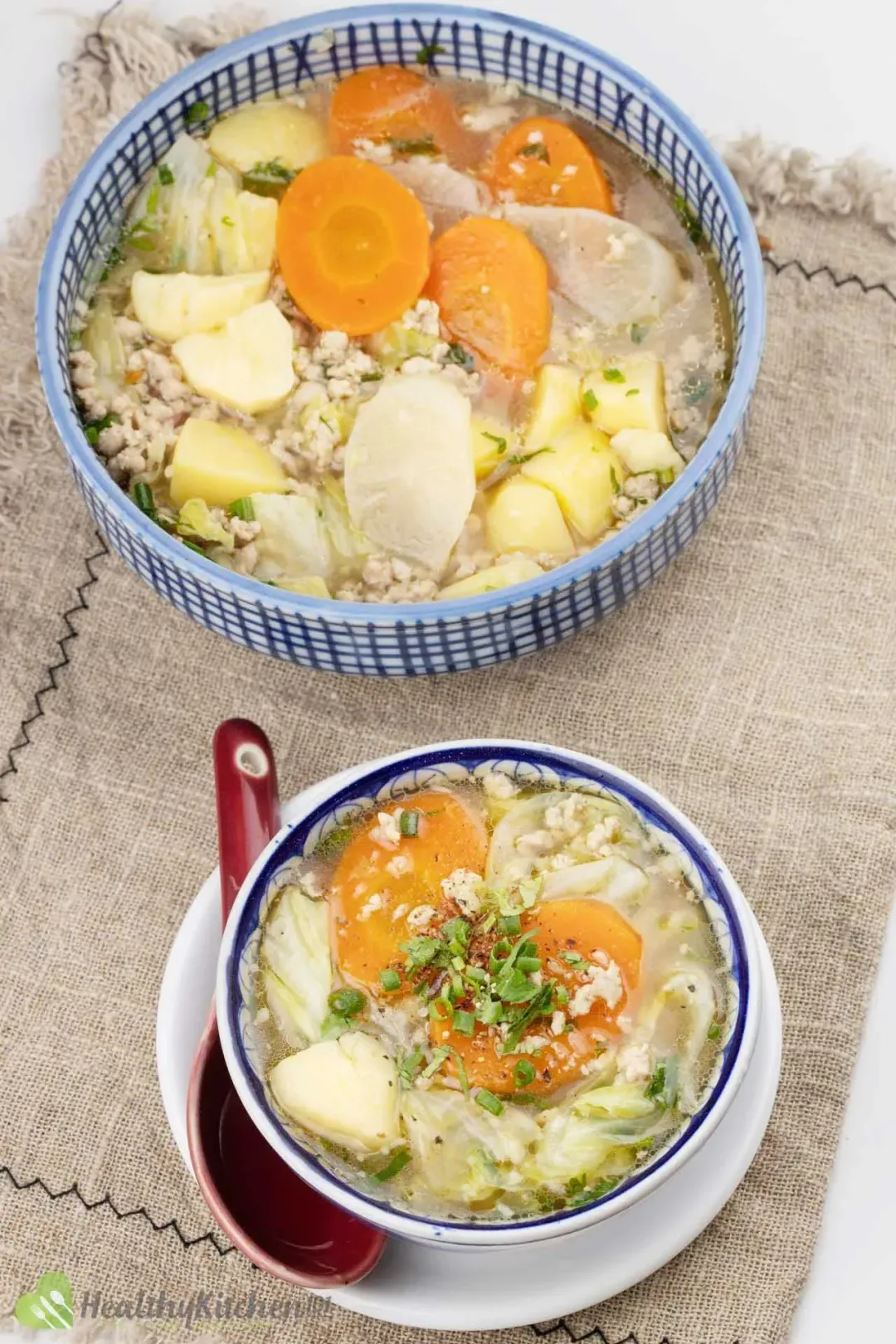 A large bowl and a small bowl of cabbage potato soup cooked with ground pork and lots of green onions