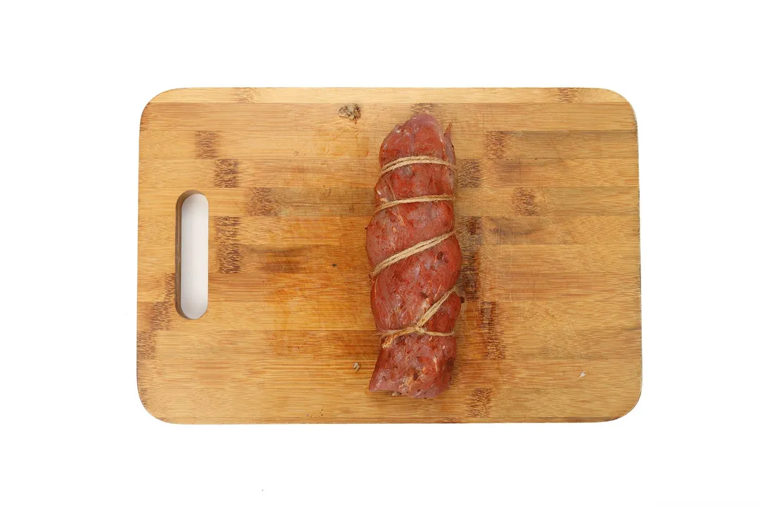 wrapped pork loin on a cutting board