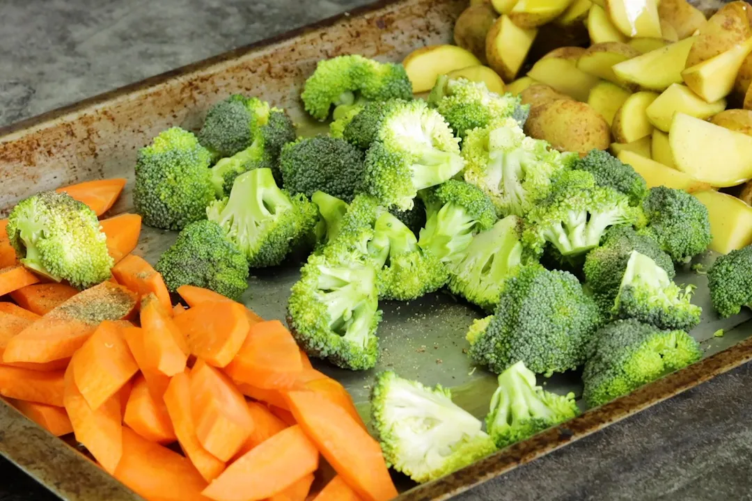 carrot cubed, broccoli floret and potato halved on a baking sheet
