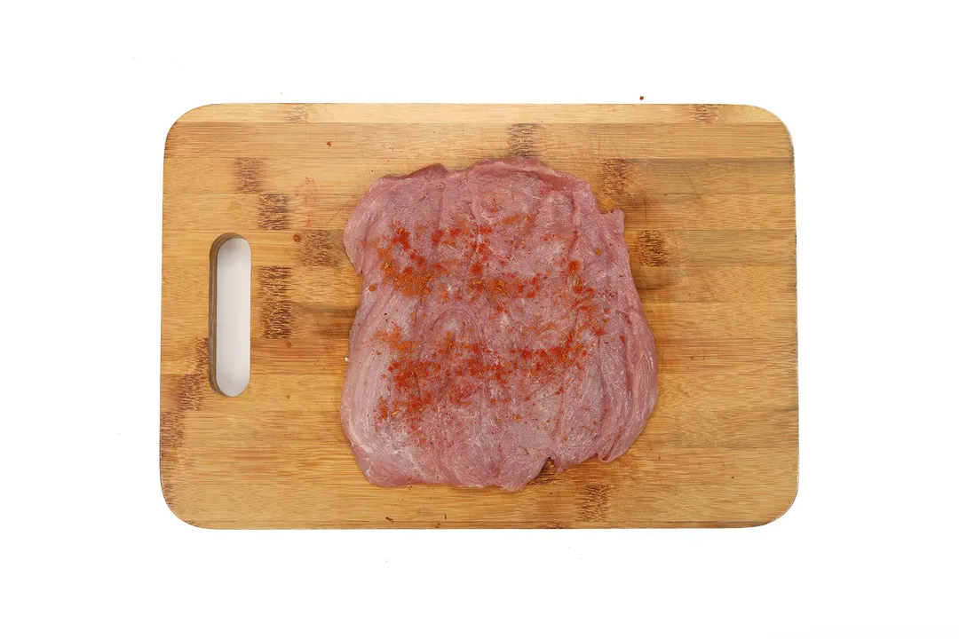 season pork loin on cutting board with cajun and paprika