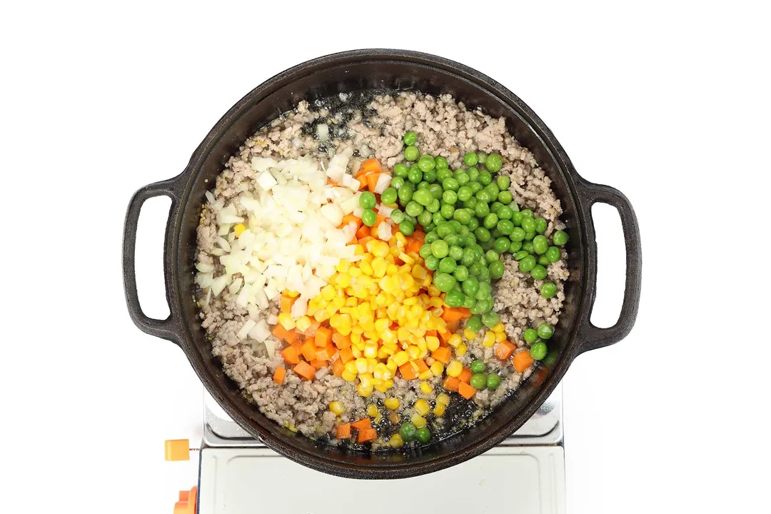 cooking rice with vegetables and peas in a skillet