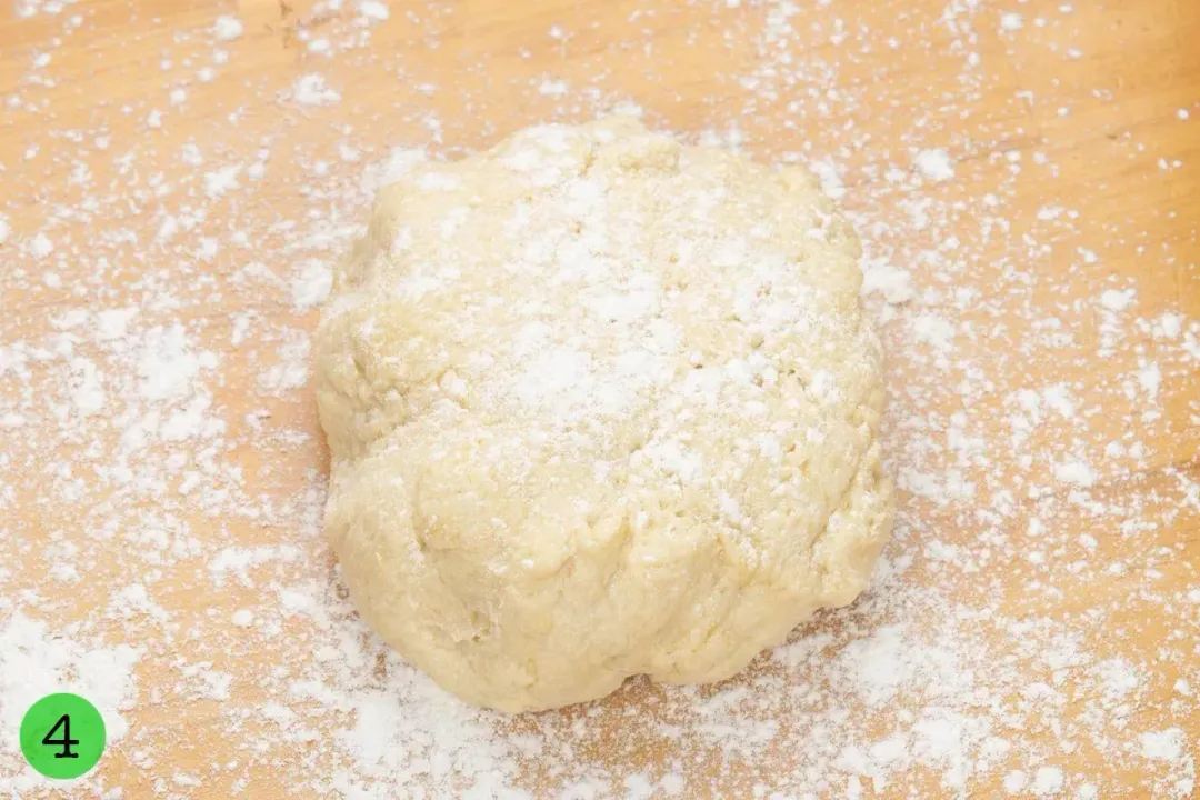 A large piece of dough lightly dusted with flour on a wooden work surface