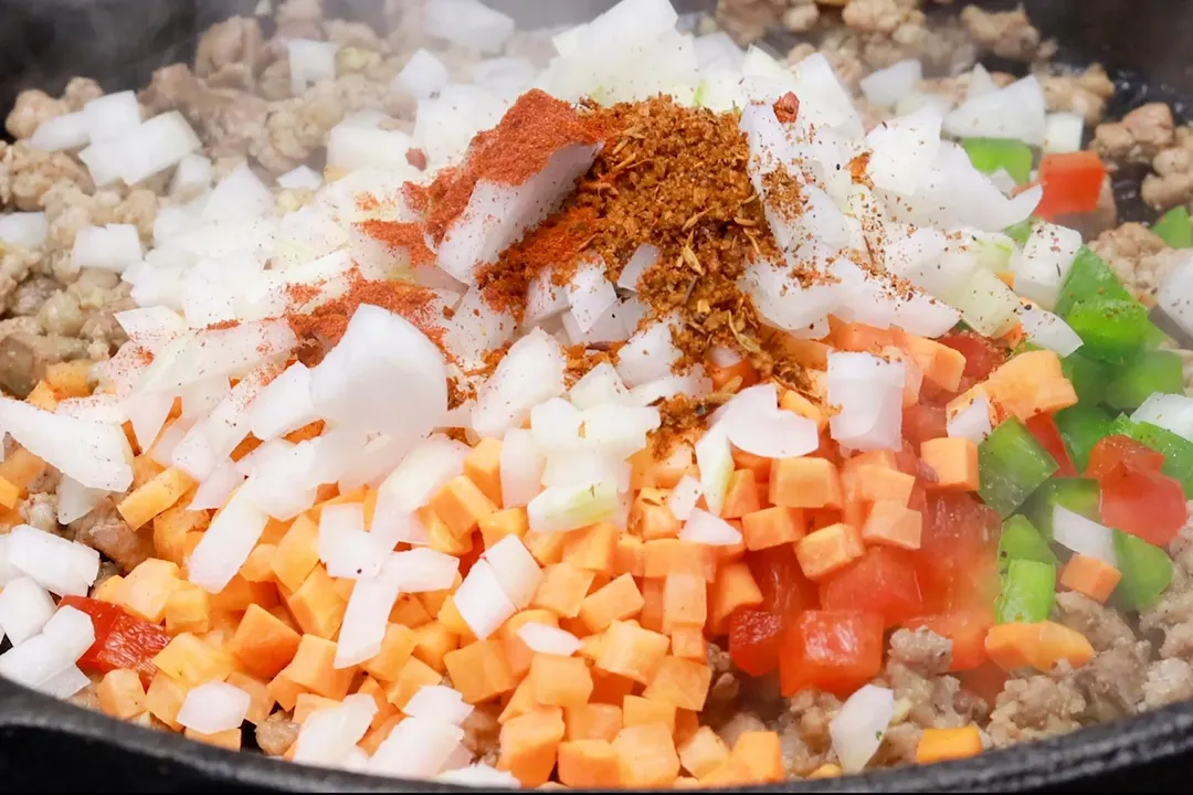 diced onion, chopped carrot and seasoning cooking in a skillet