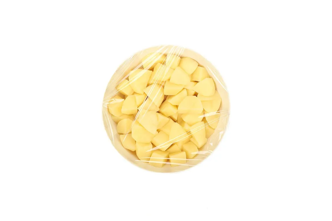 potatoes cubes in a bowl covered with a plastic wrap