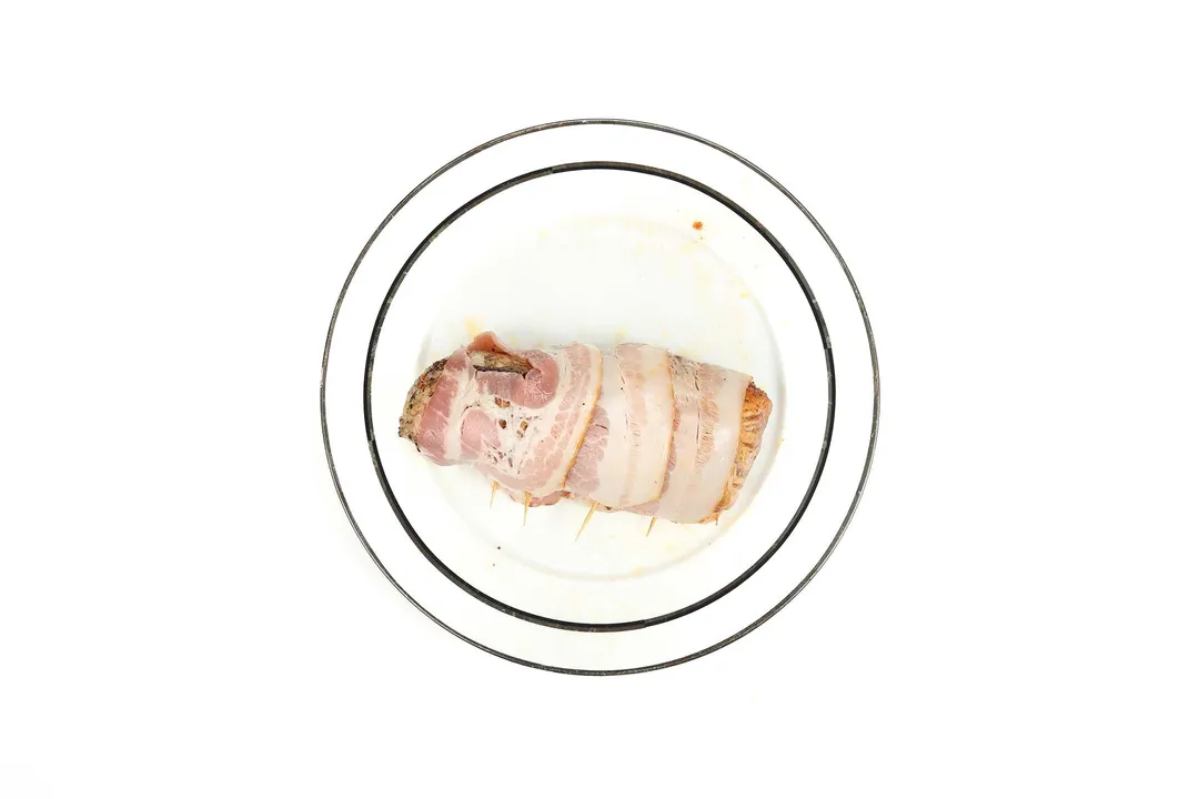 three bacon strip wrapped a pork tenderloin on a plate