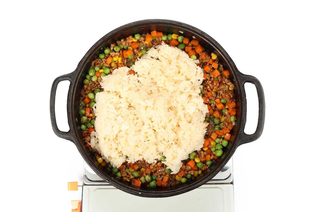 seasoned rice and ground pork, veggies cooking in a skillet