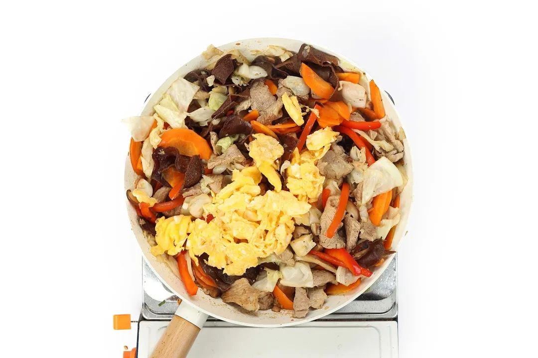 cooking pork and vegetables and eggs in a skillet