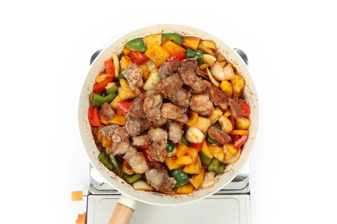 pork cubes and veggies cooking in a skillet