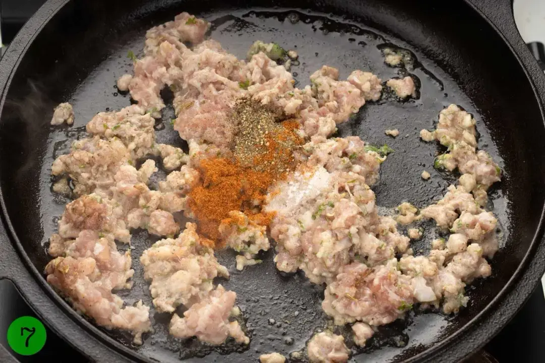 Ground meat and spices sizzling in a black cast iron skillet