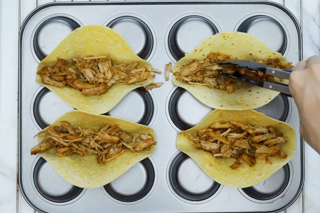 shredded meat in four tortillas on a tray