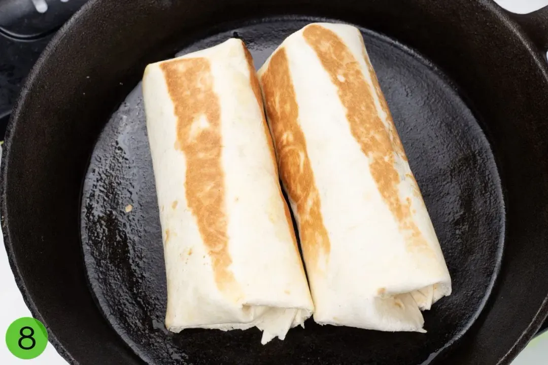 Two flour burritos browned inside a cast iron skillet