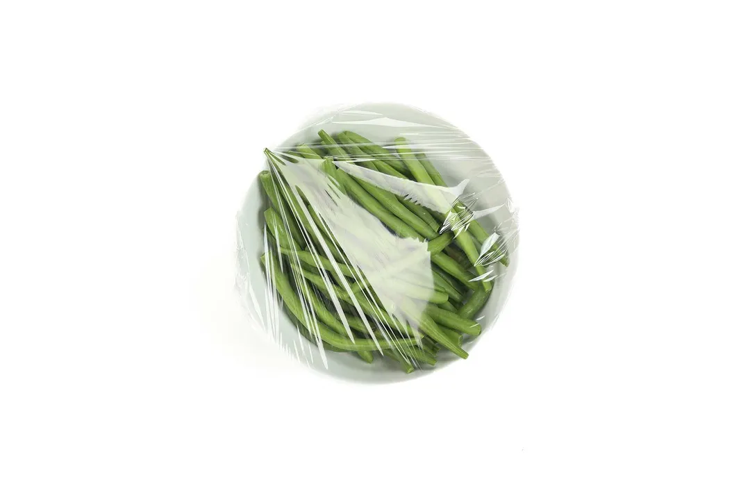a bowl of green beans wrapped by plastic wrap