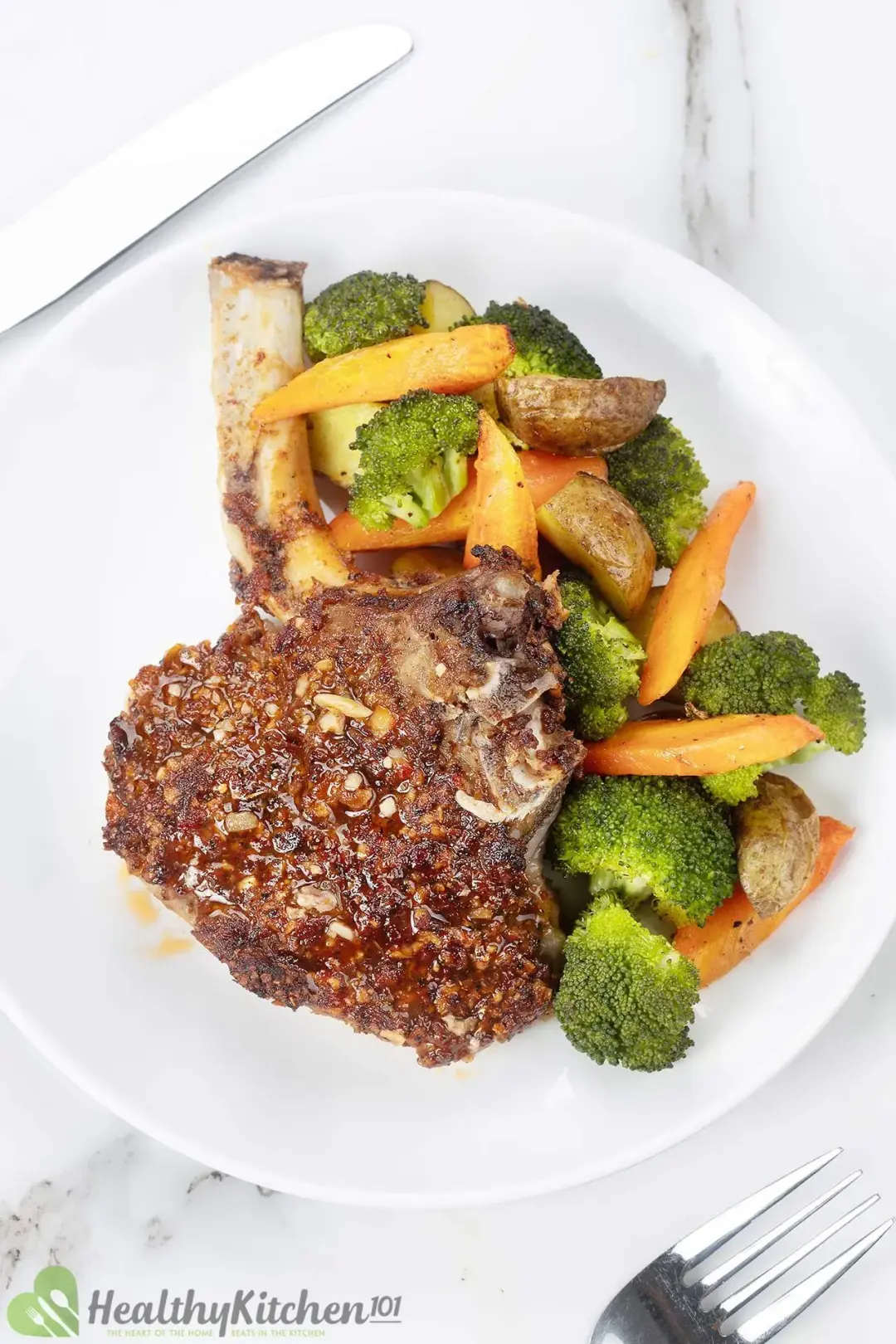 A plate of a golden pork cutlet served with cooked broccoli and carrot slices