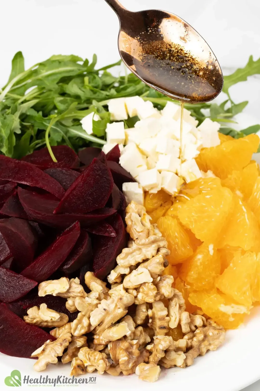 A salad with beets, feta cheese, and a dressing on top served on a white plate.