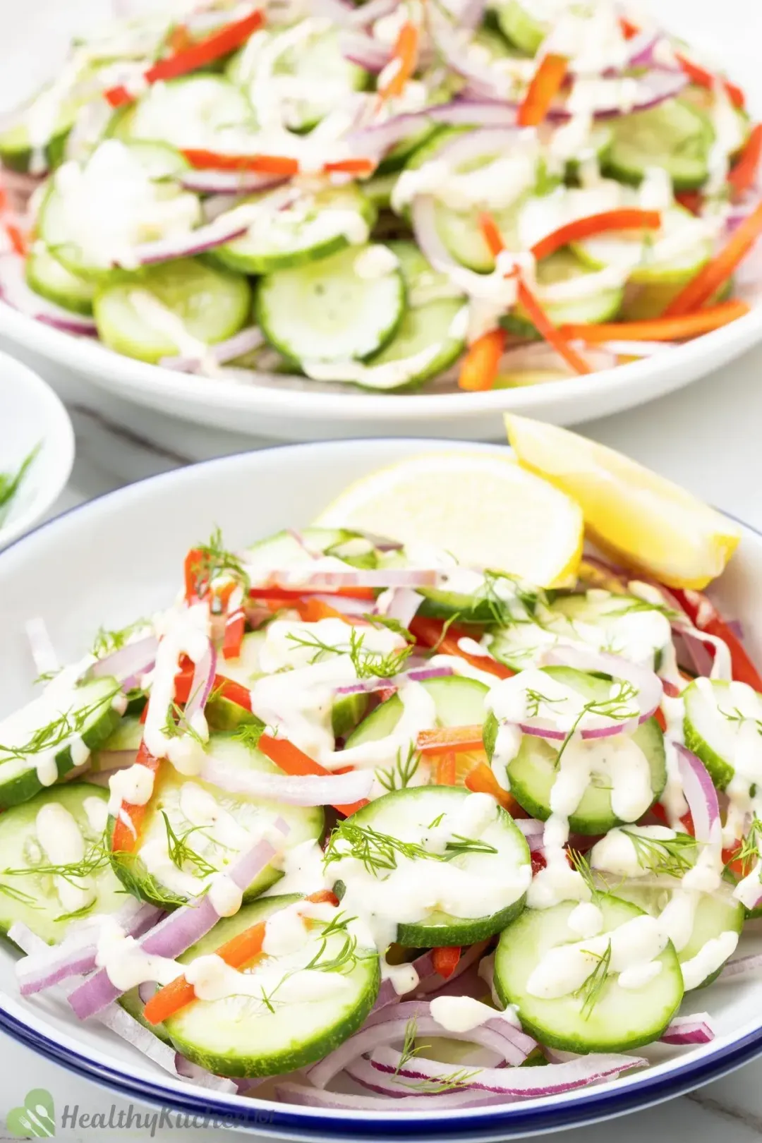 Three plates of cucumber salad: sliced cucumber, sliced red peppers, lemon slices, and dill sprinkles