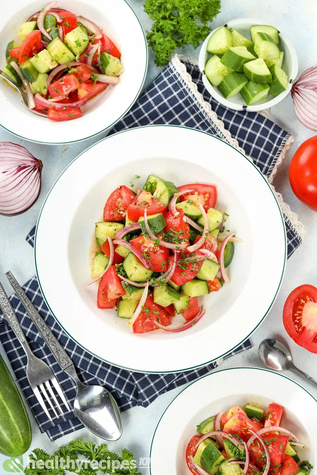 A high-angle shot of plates of cucumber tomato salad laid near various items
