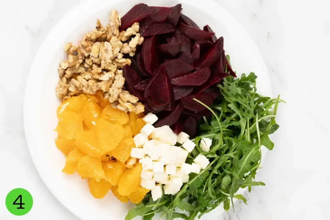 A salad with beets, feta cheese, and greens arranged on a plate.