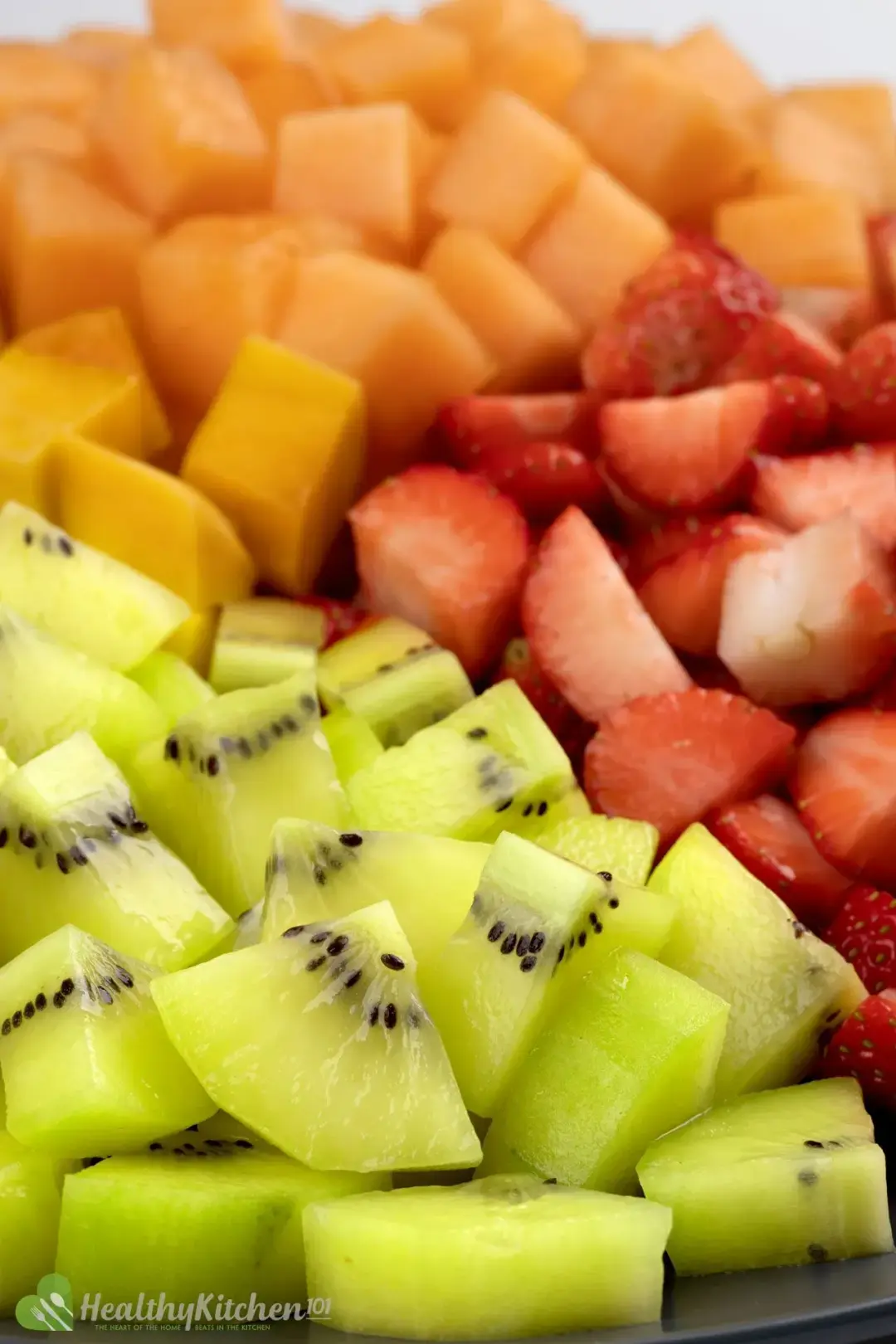 A close-up of a mixed fruit salad with watermelon, cantaloupe, honeydew, grapes, and blueberries.