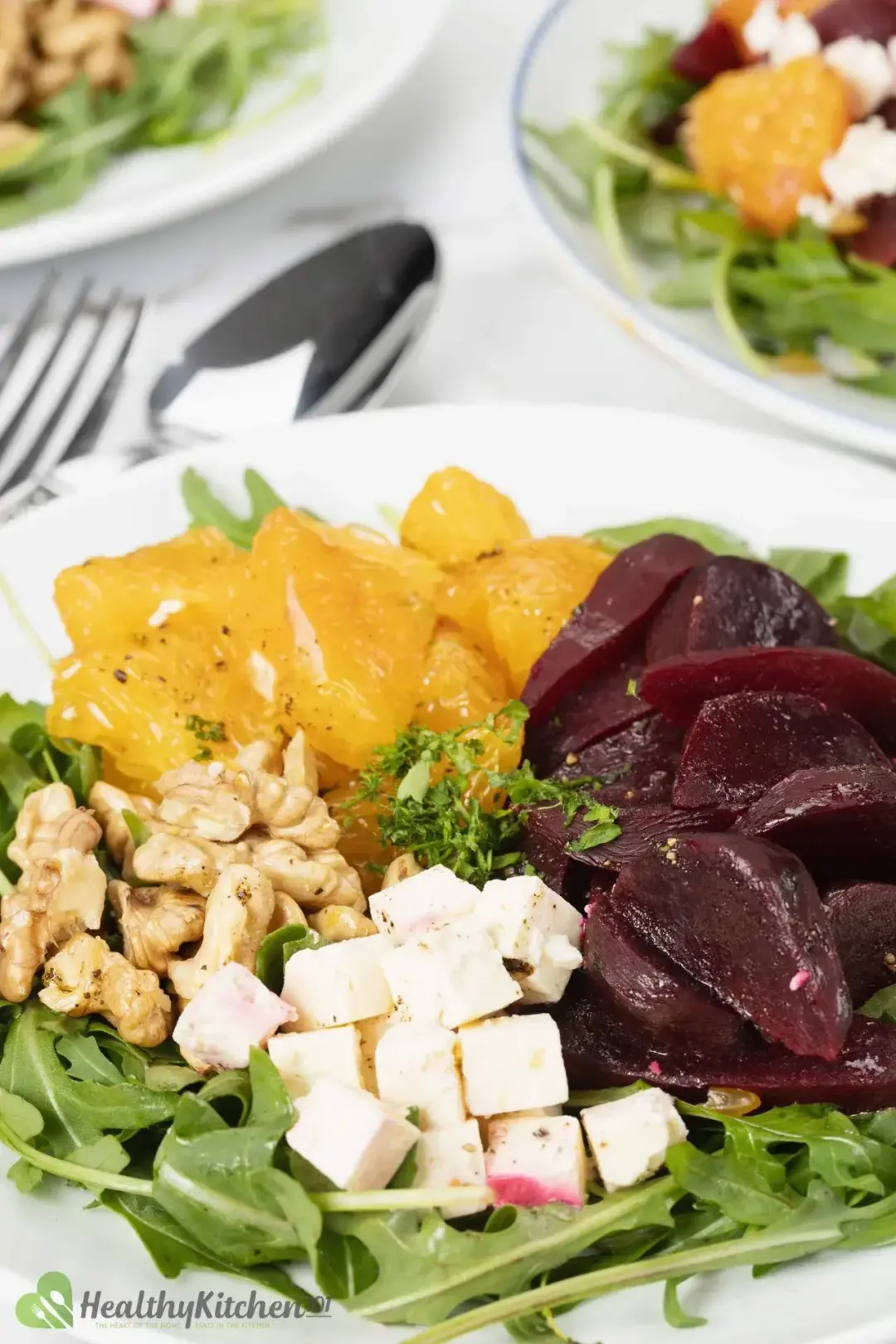 A bowl of beet and feta cheese salad with arugula, oranges, and walnuts.