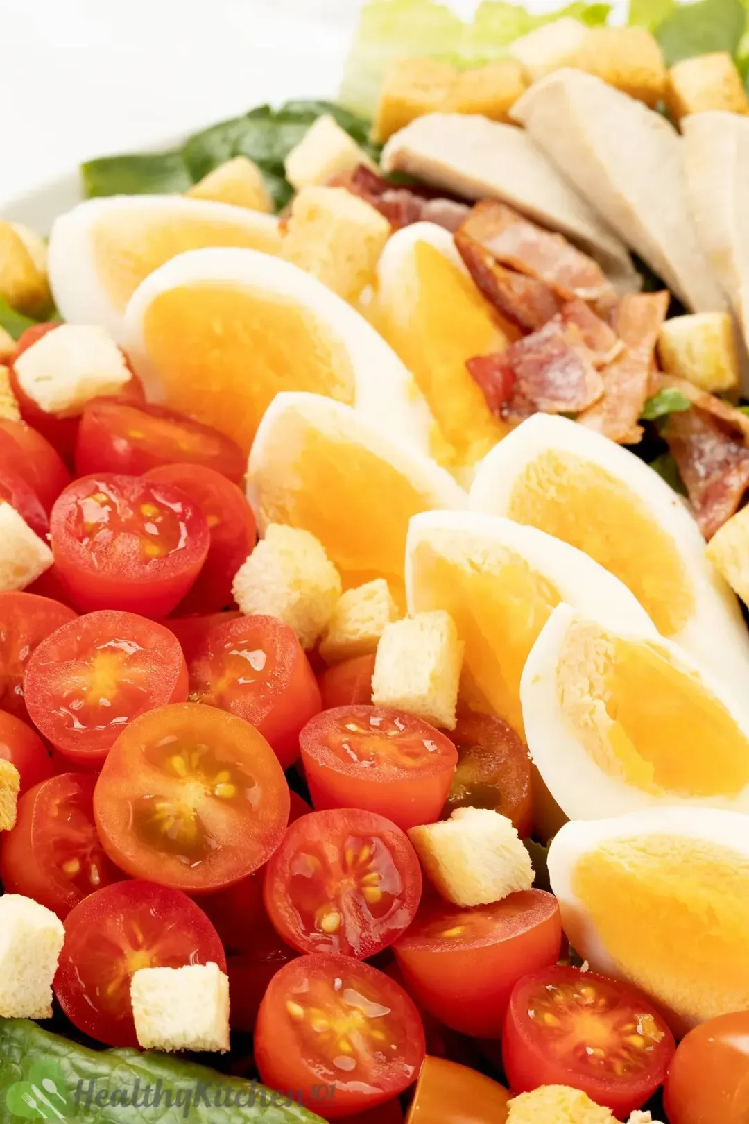 A bowl of homemade Caesar salad with lettuce, cherry tomatoes, eggs, and others