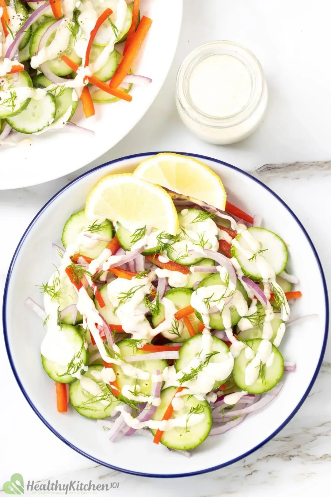 Healthy cucumber salad on two plates with sliced cucumbers, sliced red peppers, red onions, and a light dressing.