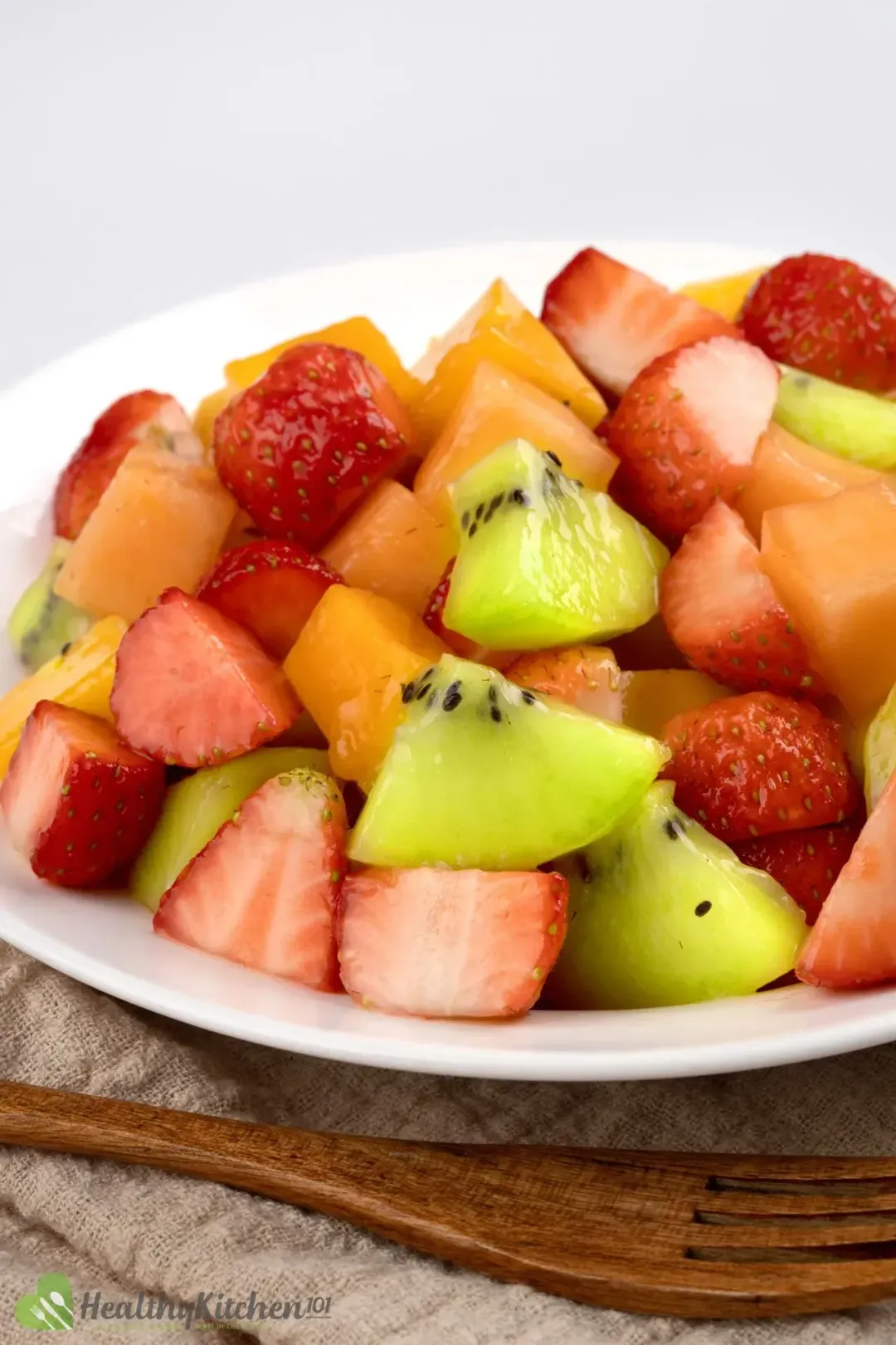 A bowl of fruit salad with strawberries, kiwi, mangoes