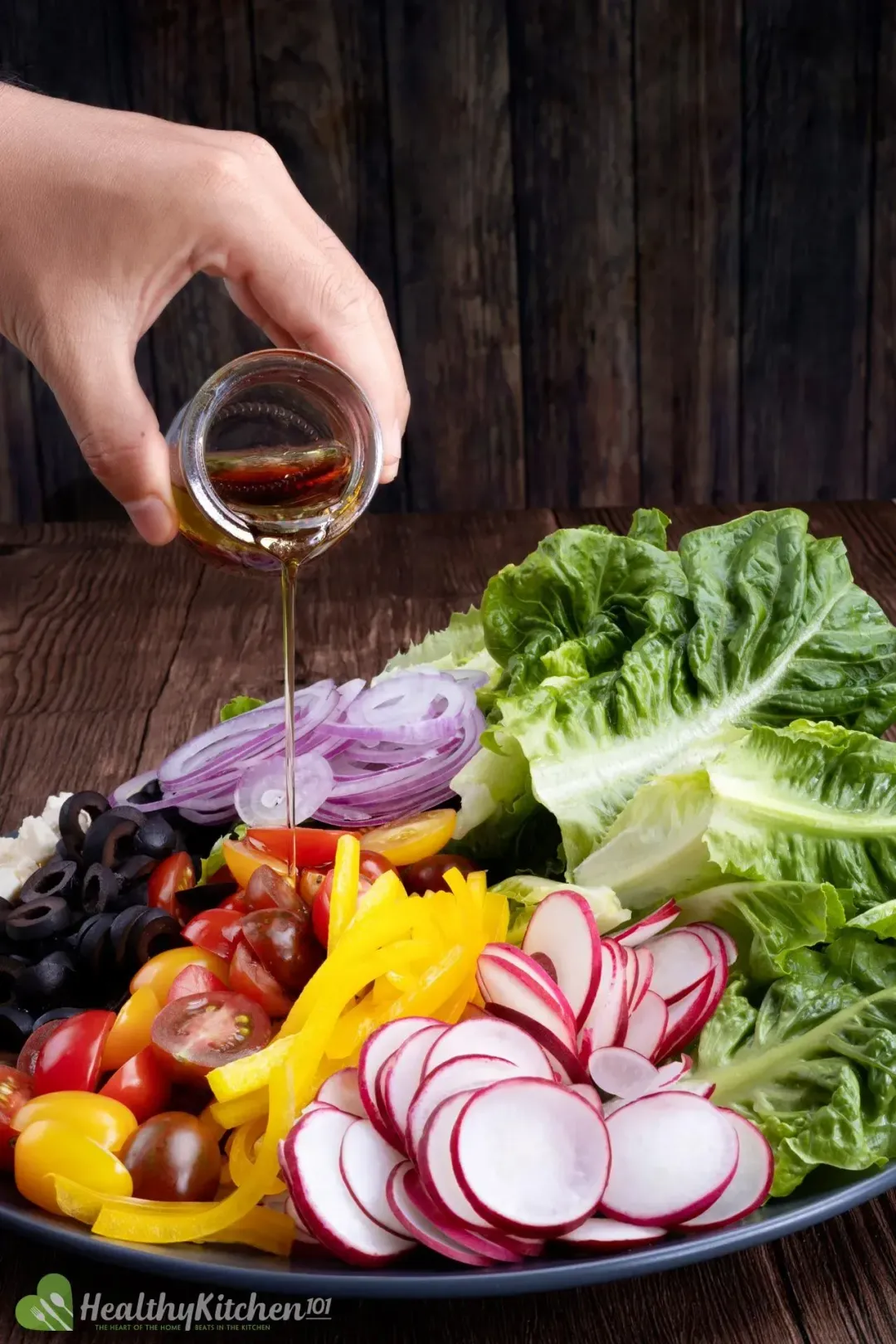 A vinaigrette dressing poured on top of a plate full of vibrant salad vegetables