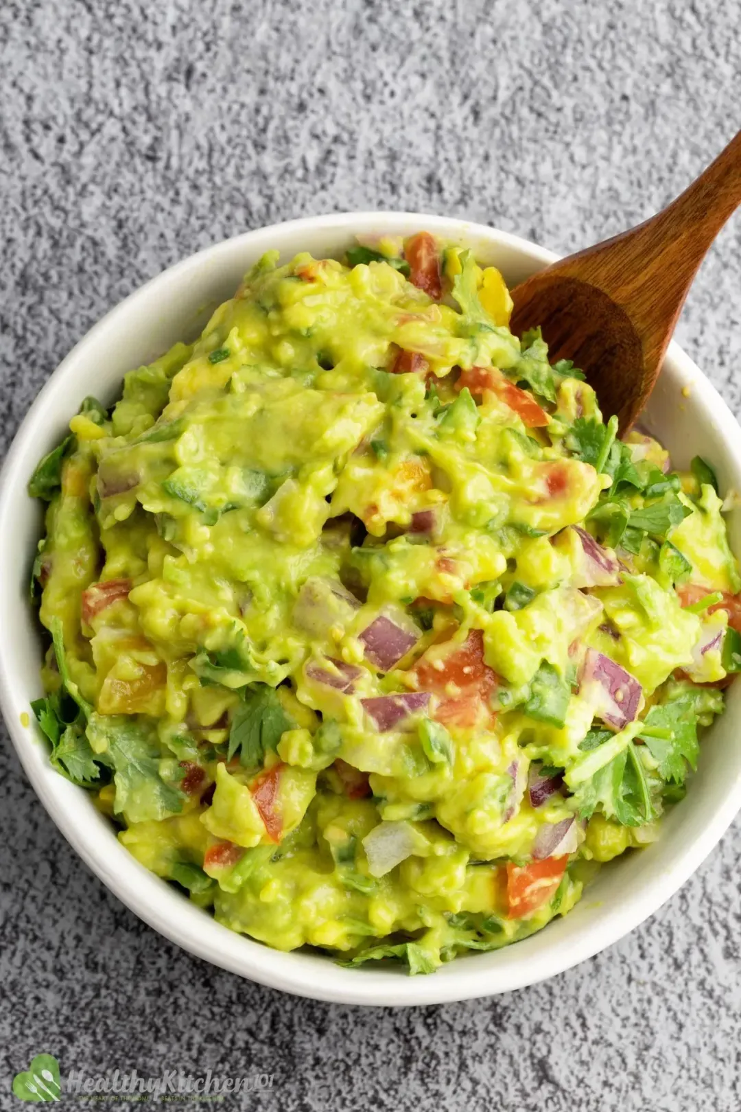 A bowl of guacamole with a wooden spoon