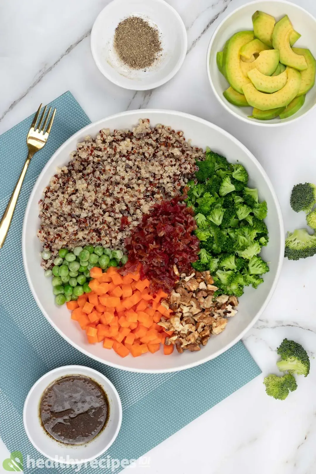 A bowl of quinoa salad with diced vegetables and herbs on top.