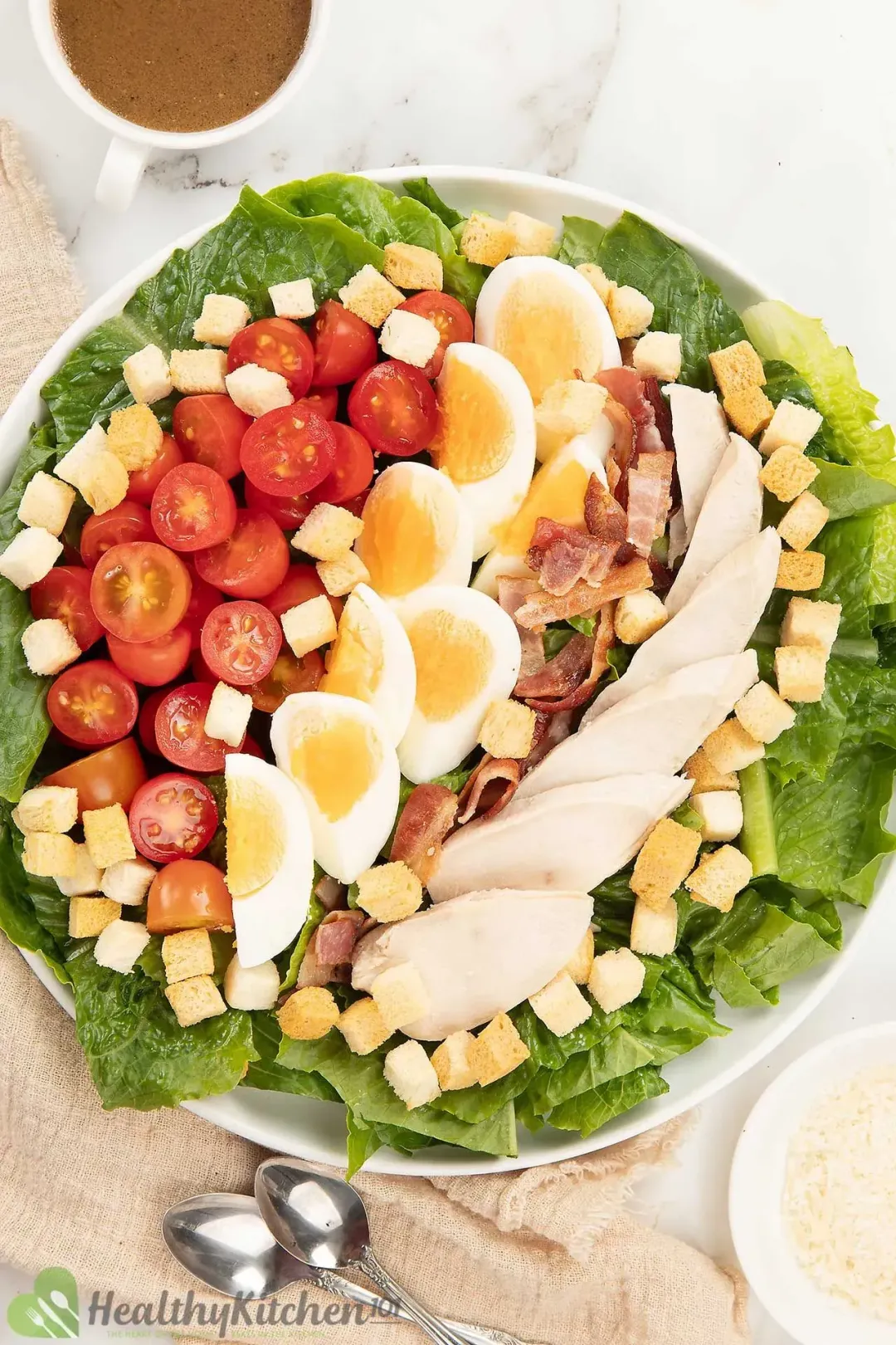 A plate of Caesar salad with lettuce, croutons, eggs quarters, chicken slices, and dressing.