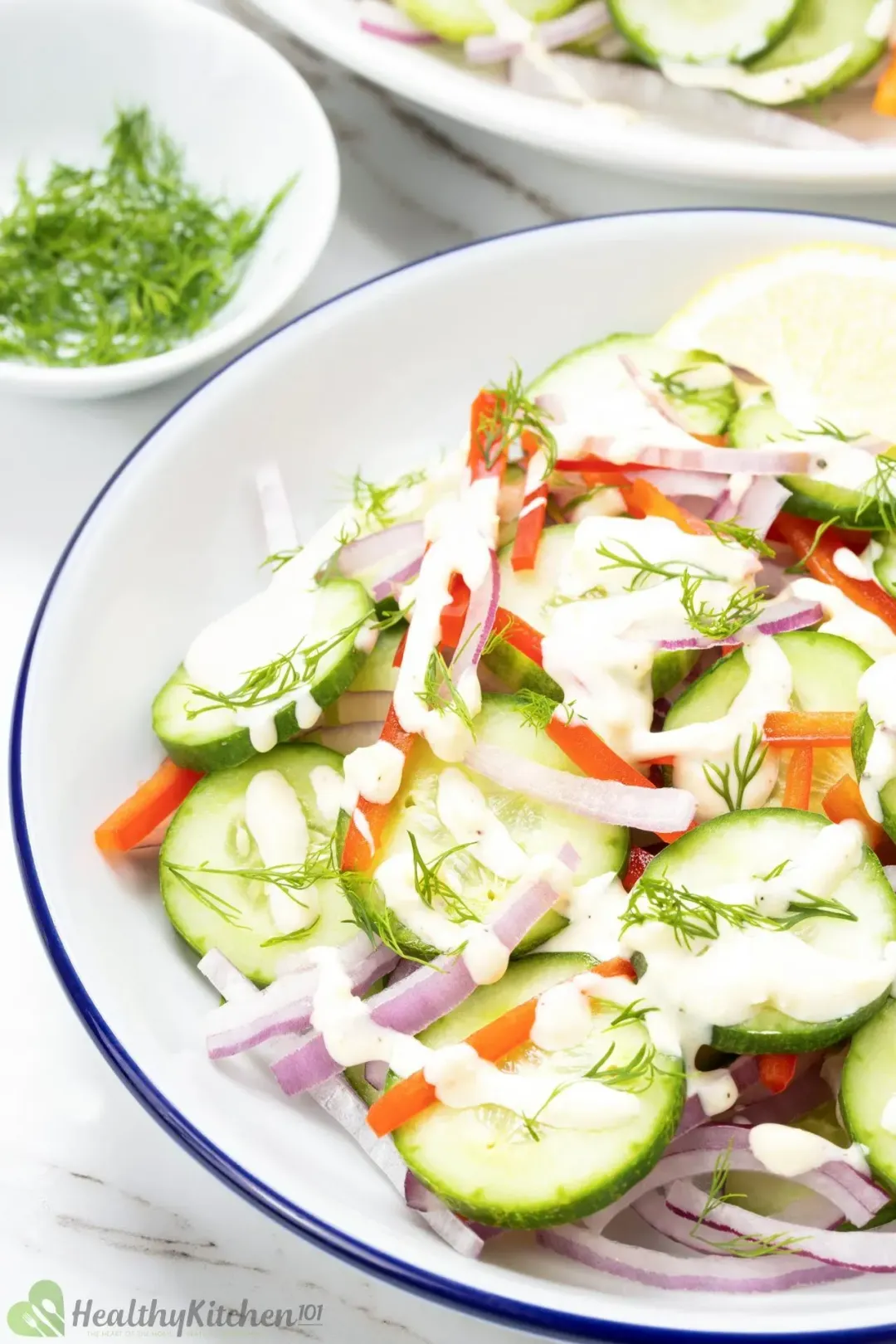 A bowl filled with sliced cucumbers, sliced red peppers, and onions