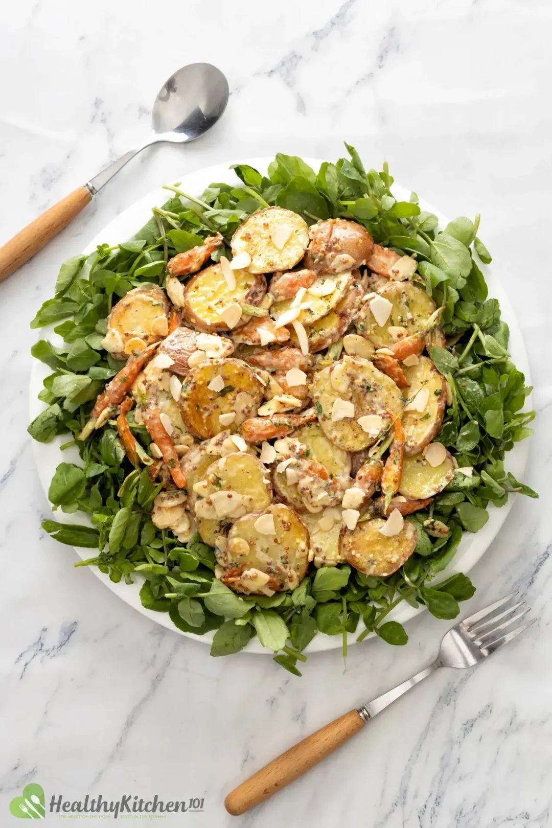 A platter of mustard potato salad with sliced potatoes, shaved almonds, watercrest, and baby carrots